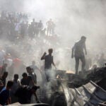 Palestinians inspect the rubble of destroyed buildings.