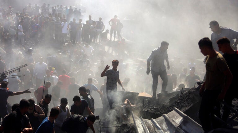 Palestinians inspect the rubble of destroyed buildings.