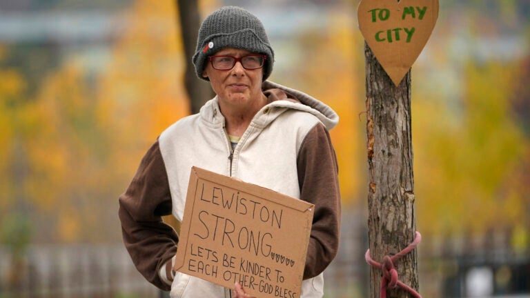 A woman stands outside with a sign in hand that reads "Lewiston strong" following a mass shooting.
