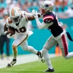 Tyreek Hill #10 of the Miami Dolphins stiff arms Jack Jones #13 of the New England Patriots during the second quarter at Hard Rock Stadium on October 29, 2023 in Miami Gardens, Florida.