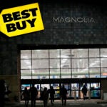 Shoppers are silhouetted as they walk toward a Best Buy store.