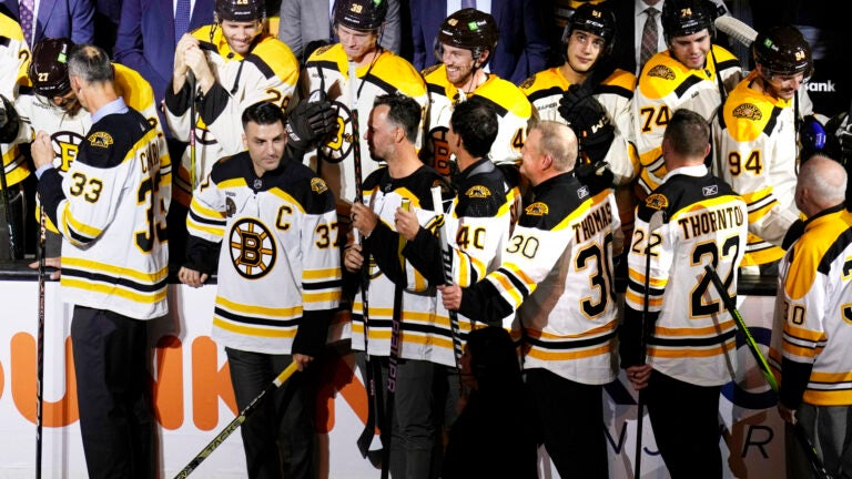 Boston Bruins alumni stand in front of this season's team during a celebration for the 100th year of the NHL hockey team, prior to the team's home-opener against the Chicago Blackhawks on Wednesday, Oct. 11, 2023, in Boston.