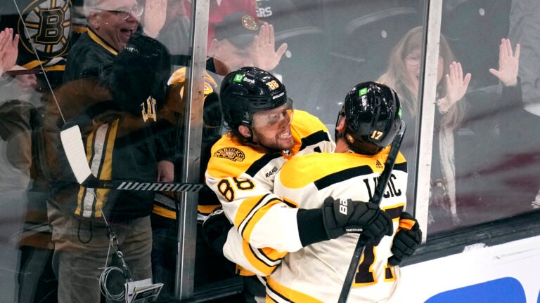 Boston Bruins right wing David Pastrnak (88) is embraced by Milan Lucic after his goal against the Chicago Blackhawks during the second period of an NHL hockey game Wednesday, Oct. 11, 2023, in Boston.