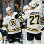 Boston Bruins center Matthew Poitras, left, celebrates his goal with the bench during the third period of an NHL hockey game against the Anaheim Ducks Sunday, Oct. 22, 2023, in Anaheim, Calif.