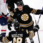 Boston Bruins center Matthew Poitras, top, celebrates his goal against the Washington Capitals during the third period of a preseason NHL hockey game Tuesday, Oct. 3, 2023, in Boston.