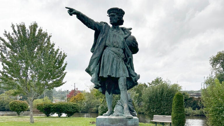 A statue of Christopher Columbus stands in a park.