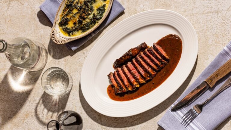 Photo d'un steak Poivre à côté d'une assiette séparée d'épinards à la crème.