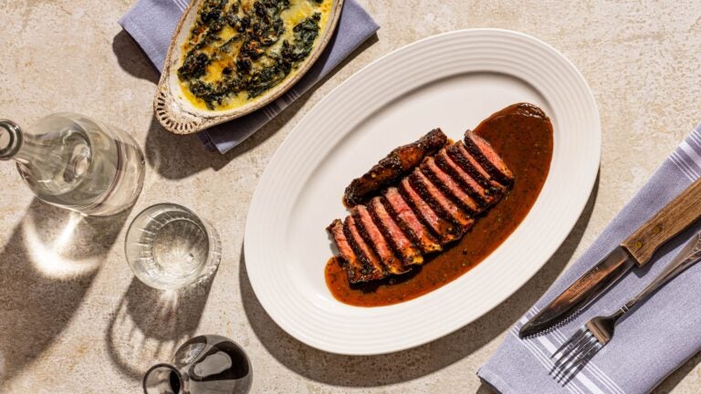 A picture of steak au poivre next to a separate dish of creamed spinach.