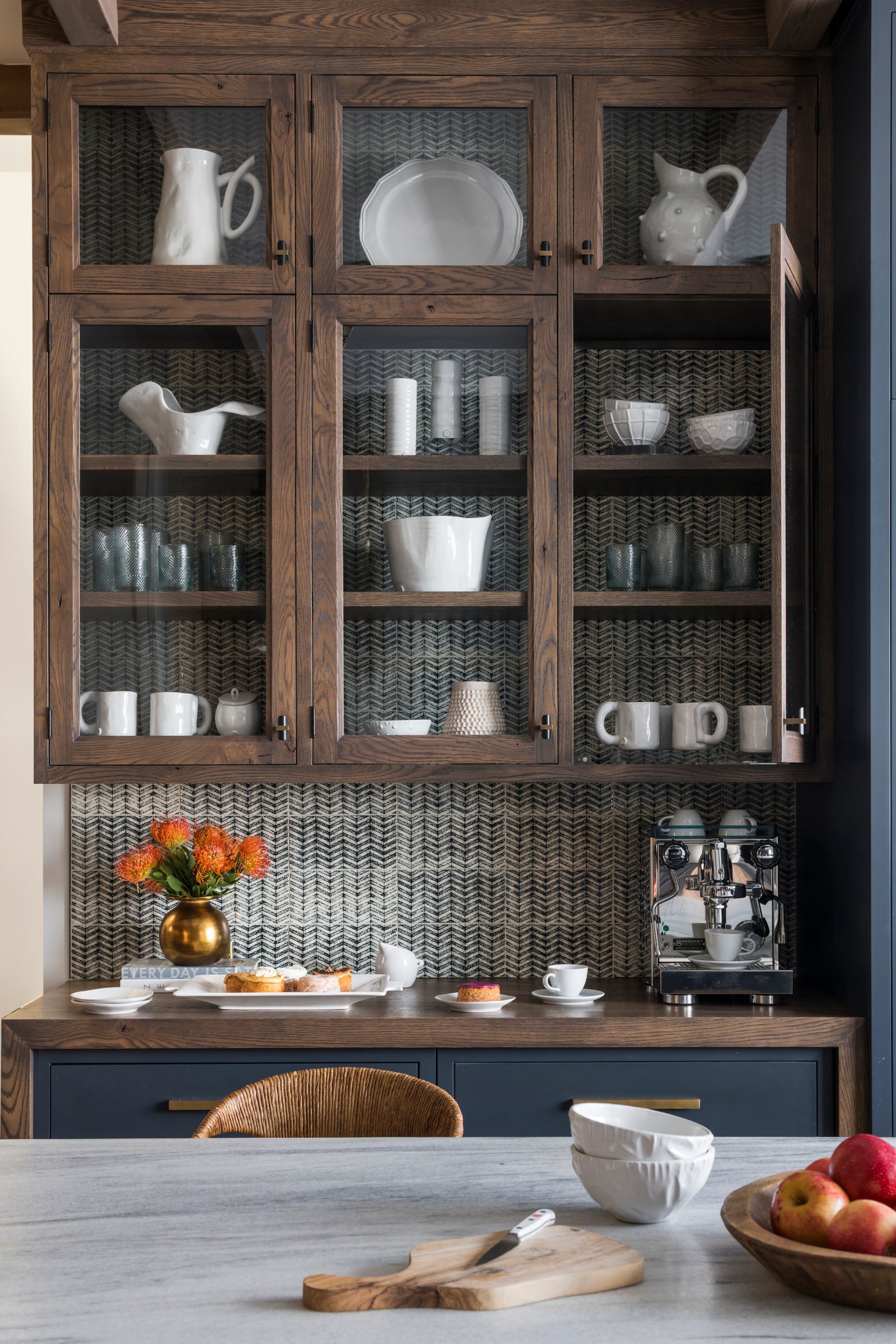 Counter with coffee maker, and upper cabinets with mugs and glasses.