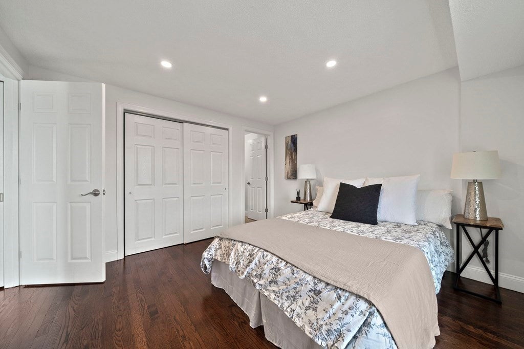 Bedroom with wood floors, and white walls in Dorchester apartment. 