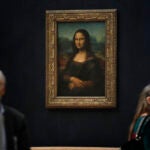 Journalists walk past Leonardo da Vinci's Mona Lisa during a visit of the Louvre museum.
