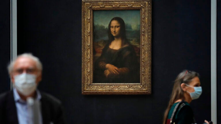 Journalists walk past Leonardo da Vinci's Mona Lisa during a visit of the Louvre museum.