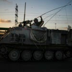 An Israel soldier gestures to passers-by as he drives a military vehicle near the border between Israel and Gaza Strip.