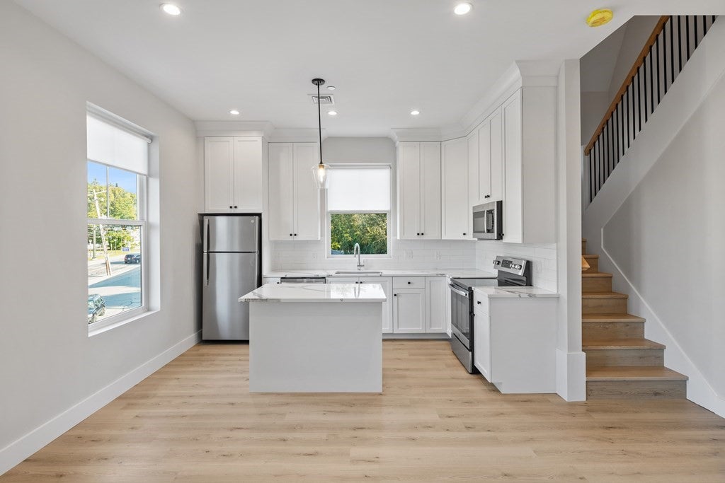 Kitchen with tall white cabinets and wood flooring, heated from a heat pump. 