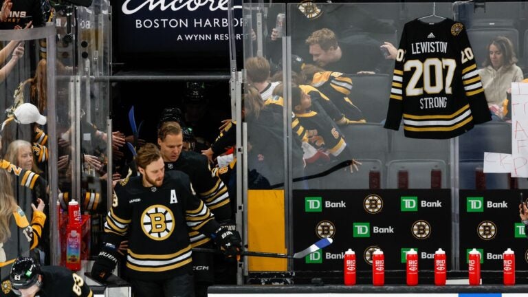 A hockey jersey hangs behind the Boston Bruins bench as a tribute to the victims of the mass shooting in Lewiston, Maine yesterday before a game between the Boston Bruins and the Anaheim Ducks at the TD Garden on October 26, 2023 in Boston, Massachusetts. The jersey says "Lewiston Strong 207" on the back.