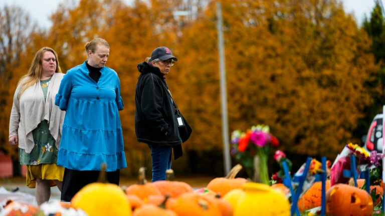 People pay their respects at a makeshift memorial outside a bowling alley in Maine.