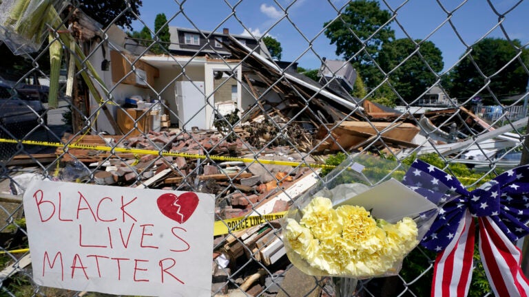 Signs and flowers are attached to a fence outside a building in Winthrop.
