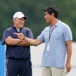 New England Patriots head coach Bill Belichick, left, smiles while speaking with former Patriots player Tedy Bruschi, right, during an NFL football practice, Tuesday, Aug. 3, 2021, in Foxborough, Mass.
