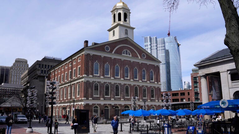 Visitors pass Faneuil Hall, April 5, 2022, in Boston.