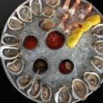 A large platter of ice with oysters and shrimp cocktail at Row 34