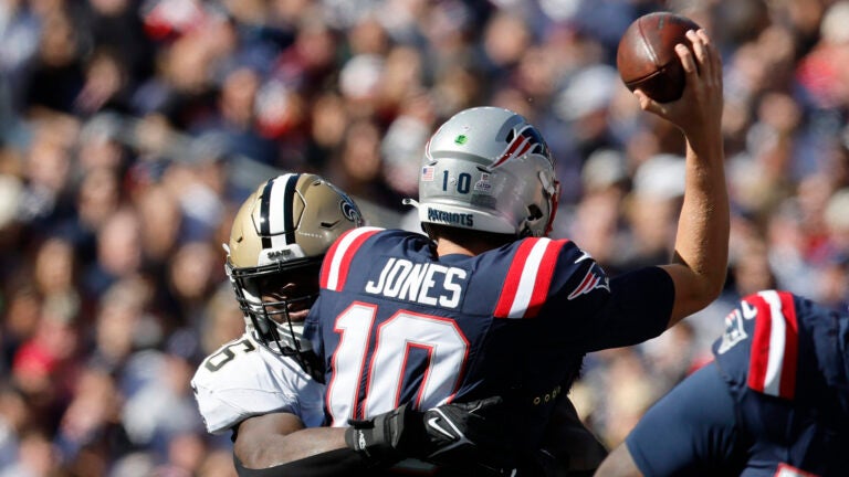 New England Patriots quarterback Mac Jones (10) tries to pass the ball under pressure from New Orleans Saints defensive end Carl Granderson, left, during the first half of an NFL football game, Sunday, Oct. 8, 2023, in Foxborough, Mass.