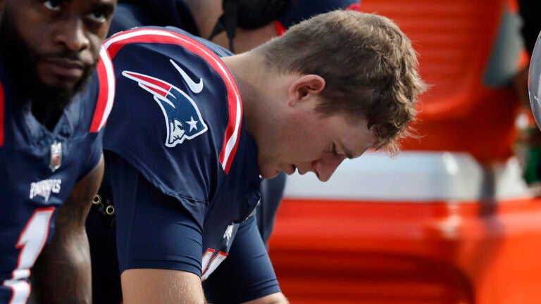 New England Patriots quarterback Mac Jones, right, is seated on bench near wide receiver DeVante Parker, left, during the first half of an NFL football game against the New Orleans Saints, Sunday, Oct. 8, 2023, in Foxborough, Mass.