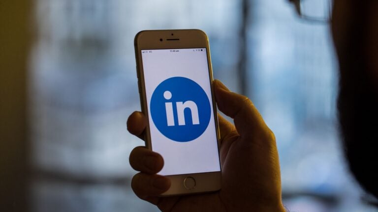 Man holding up phone with LinkedIn app on screen