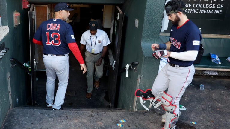 Alex Cora begins walking down the dugout tunnel as catcher Connor Wong follows from the right.
