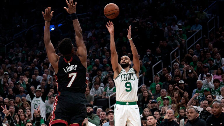 Boston Celtics guard Derrick White (9) puts up a three over Miami Heat guard Kyle Lowry (7) during the fourth quarter. - The Boston Celtics host the Miami Heat in the team’s home season opener on October 27, 2023 at TD Garden in Boston, MA.