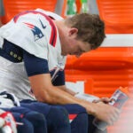 New England Patriots quarterback Mac Jones sitting on the bench after getting sacked for a saftey against the Las Vegas Raiders during fourth quarter NFL action at Allegiant Stadium.