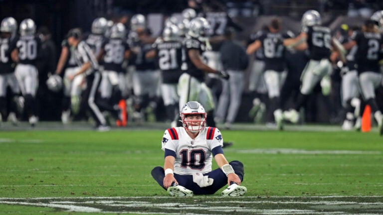 Patriots quarterback Mac Jones sits stunned on the ground as the Raiders celebrate their imnprobable last second victory behind him. The New England Patriots visited the Las Vegas Raiders for a regular season NFL football game at Allegiant Stadium.