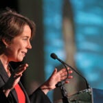 A picture of Gov. Maura Healey of Massachusetts in front of a microphone at a podium.