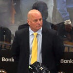 Bruins coach Jim Montgomery stands at the bench as Florida players celebrate on the ice after they beat the Bruins ion overtime.