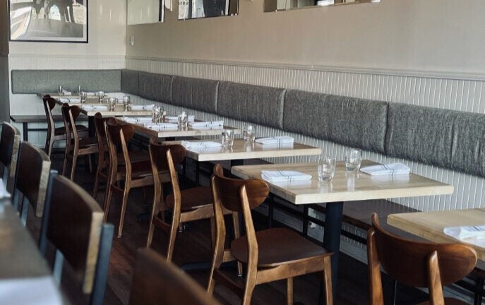 A picture of booth restaurant seating, featuring several chairs and place settings.