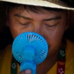 A World Youth Day volunteer uses a small fan to cool off from the intense heat.