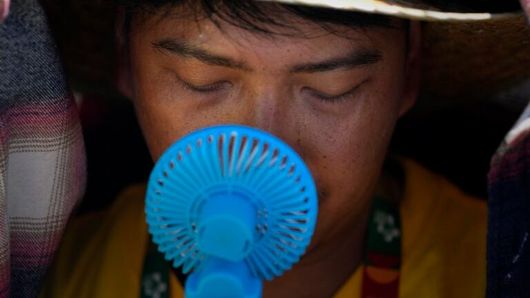 A World Youth Day volunteer uses a small fan to cool off from the intense heat.