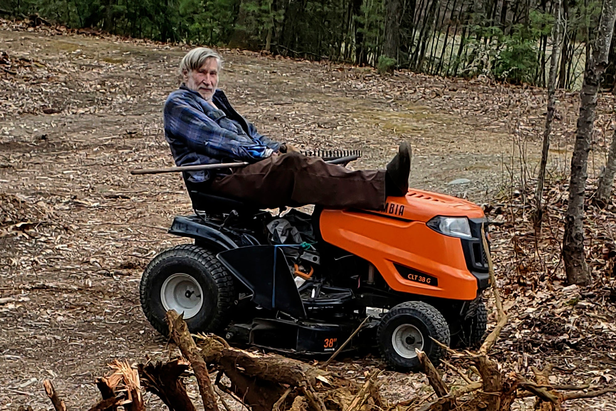 Geoffrey Holt rests his leg on top of his riding mower in Hinsdale, N.H.