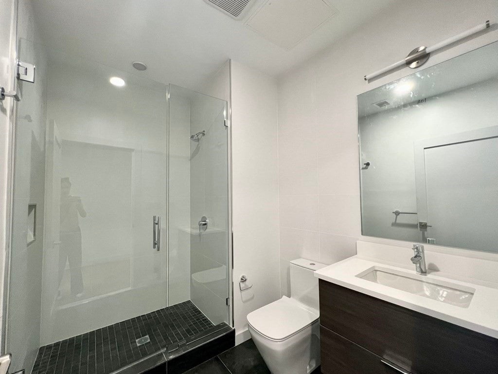 Modern bathroom with black tile flooring and glass shower. 