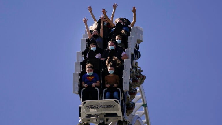 Visitors wearing masks ride on a roller coaster at Six Flags Magic Mountain in California.