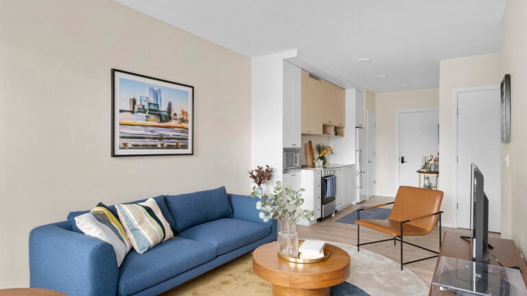 Center and Stone Apartment complex living room with a blue couch, and round wooden table.