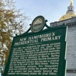 A dark green historical marker displayed outside the Statehouse in Concord, New Hampshire.