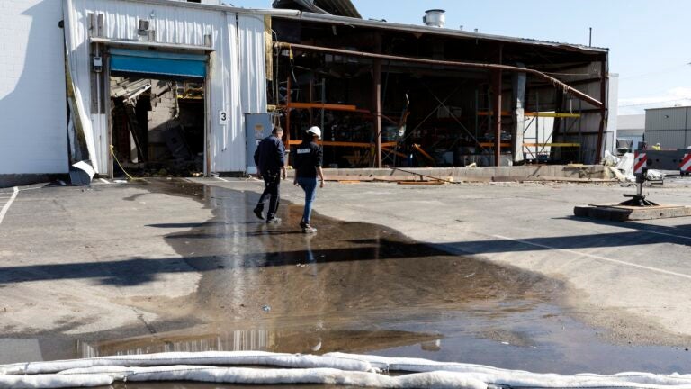 A Massachusetts Department of Environmental Protection worker walks in front of the damaged Seqens plant in Newburyport, Mass.