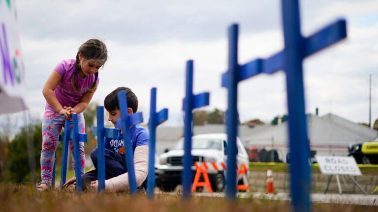 Lucy Allard, 5, and her brother Zeke Allard, 8, plant crosses in honor of the victims of this week's mass shooting in Lewiston, Maine.