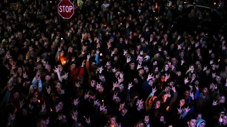 People sign "I love you," while gathered at a vigil for the victims of mass shootings in Maine.