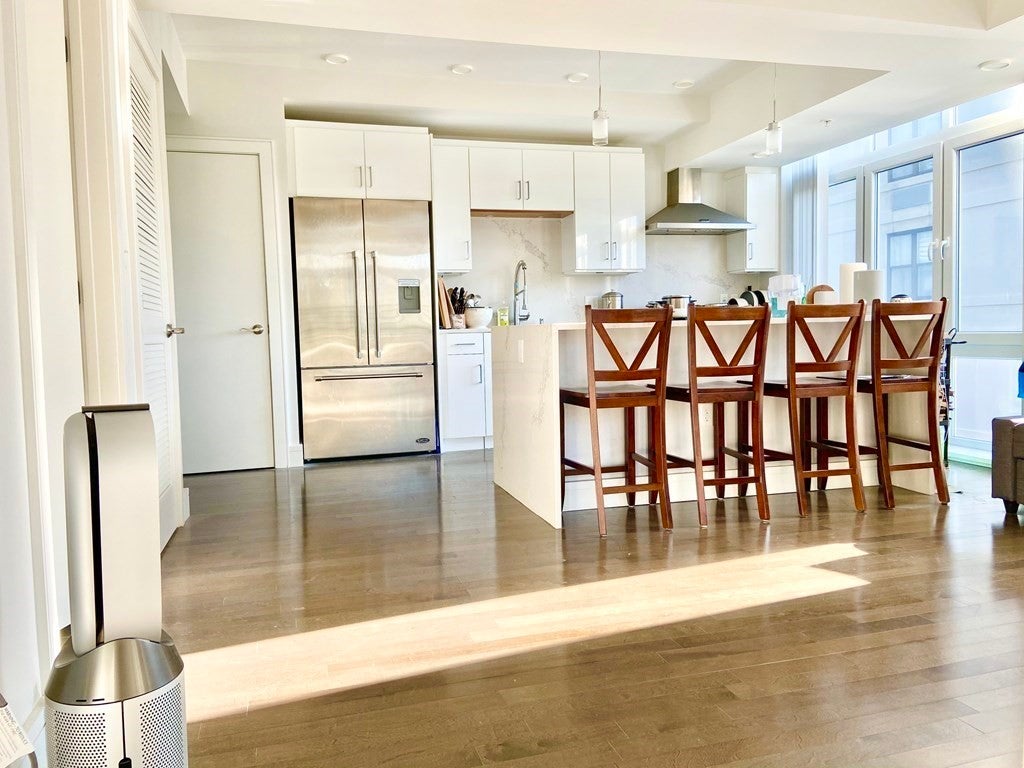 Kitchen with wood floors and sleek white cabinets. 