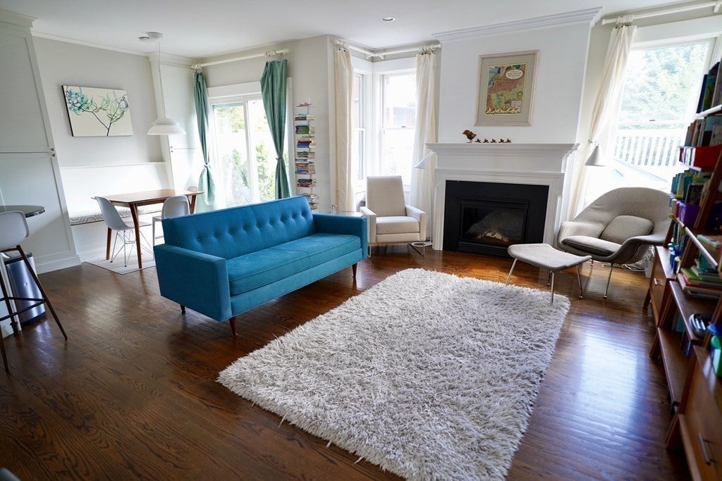 Living room with turquoise couch, wood floors, and a fireplace. 