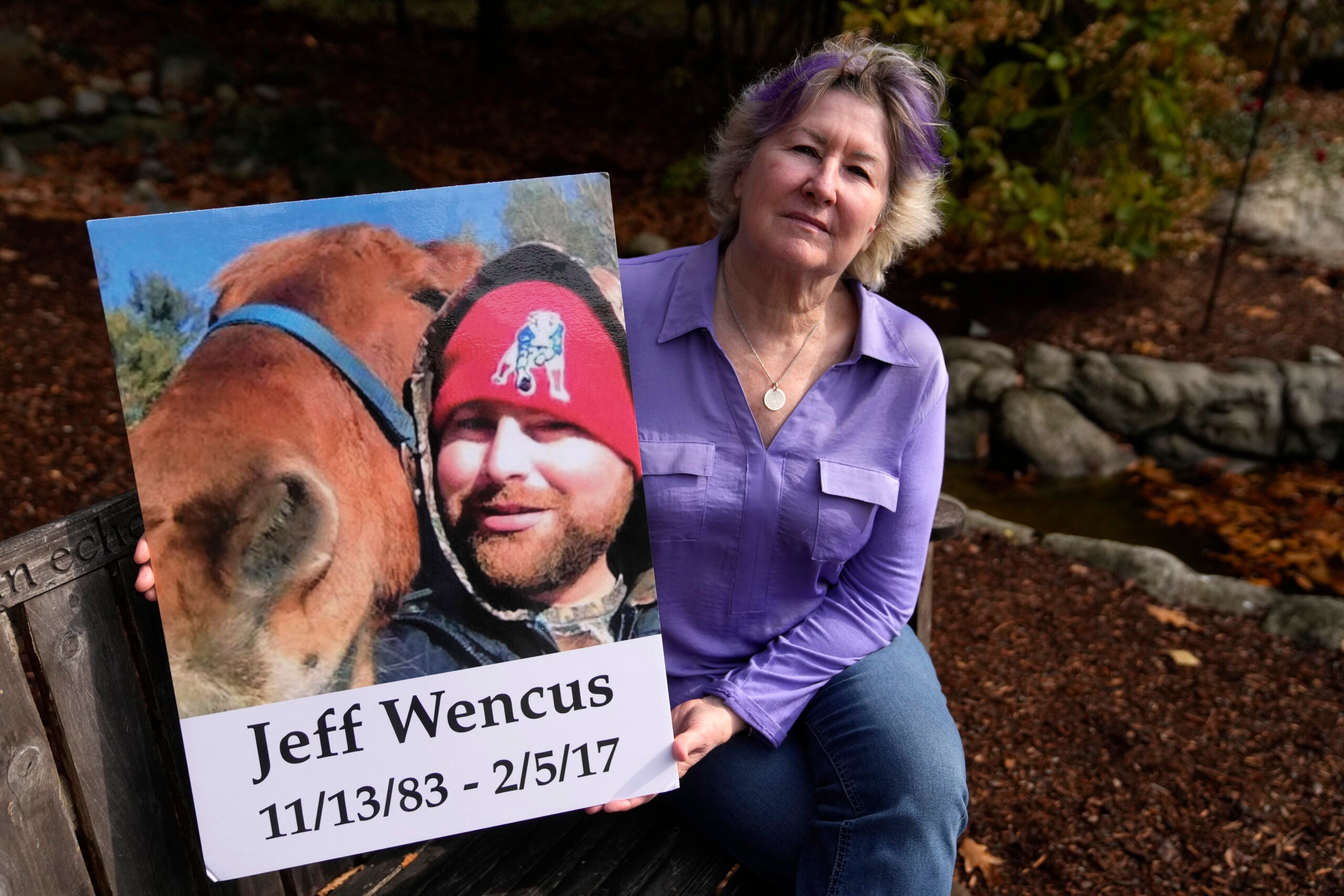 Lynn Wencus, of Wrentham, Mass., holds a photograph of her son Jeff while seated in a garden at her home.