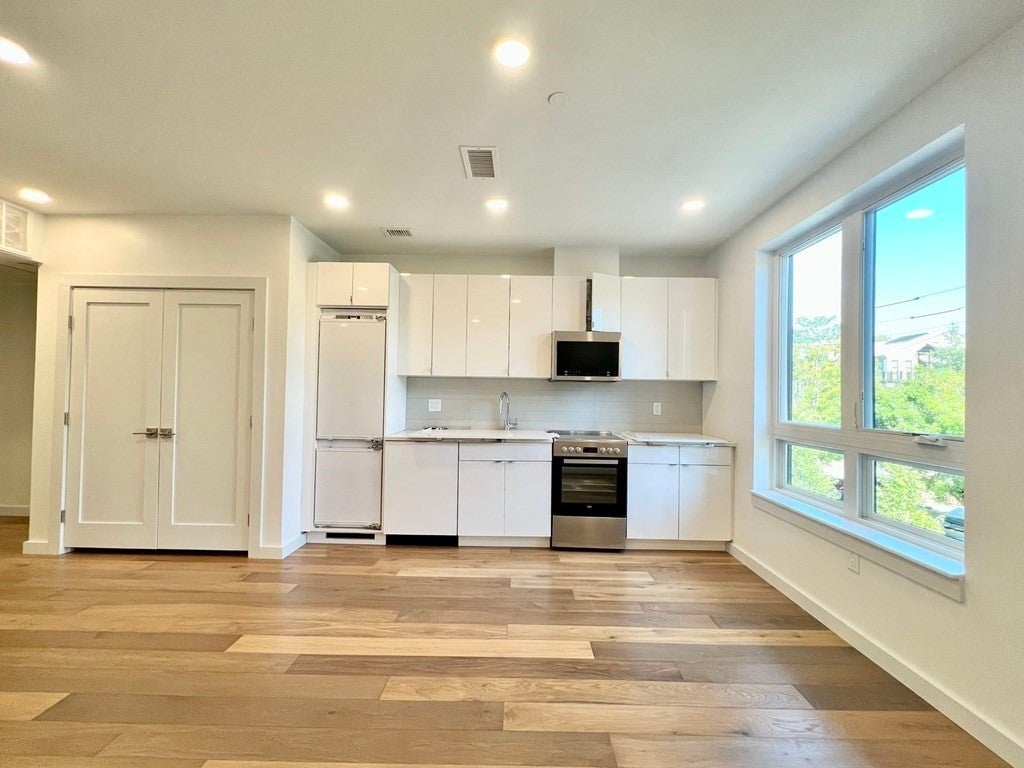 Studio in Cambridge with wood flooring and white kitchen cabinets.
