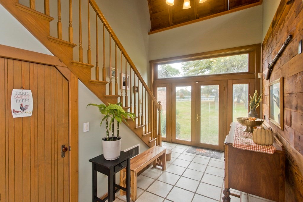 Foyer area with wood paneling, and glass front door, and stairs. 