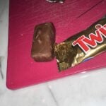A photo of a Twix candy bar next to a sewing needle, allegedly found inside the candy bar.